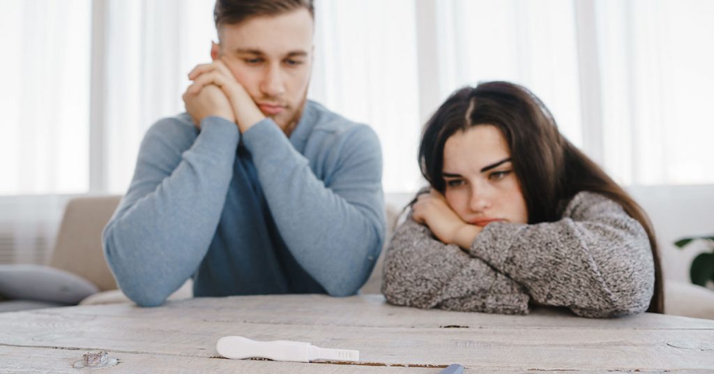Unwanted pregnancy, contraception fail, safe concept. Frustrated couple checking a pregnancy test; blog: Should You Take a Break Between IVF Cycles?
