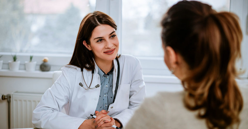 Cheerful young doctor listening to a patient in the office; blog: Should You Get Preconception Counseling?